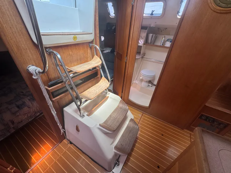 Slide: The Image of Interior of 2000 Hunter 410 sailboat with wooden steps and visible bathroom. - 46