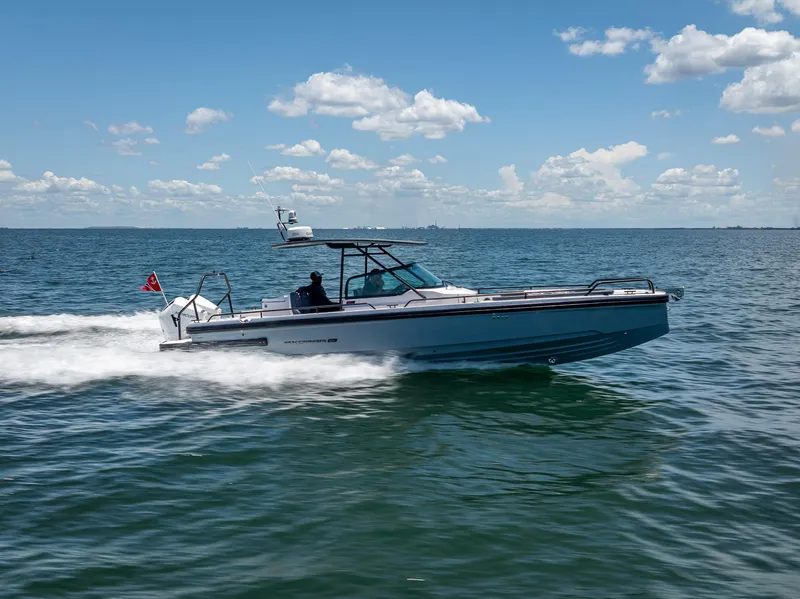 Slide: The Image of 2022 Axopar 28 T-Top Brabus cruising on open water under a clear blue sky. - 14