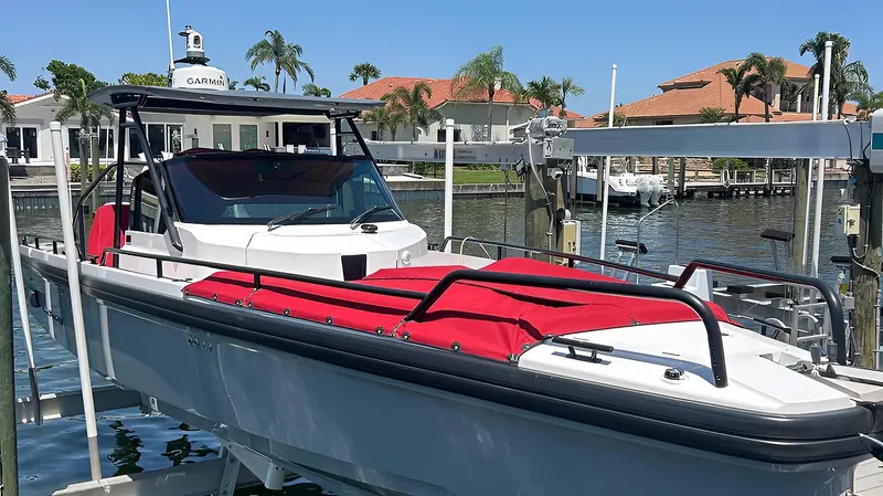 Slide: The Image of 2022 Axopar 28TT Brabus boat with red seating, docked in a sunny marina. - 44