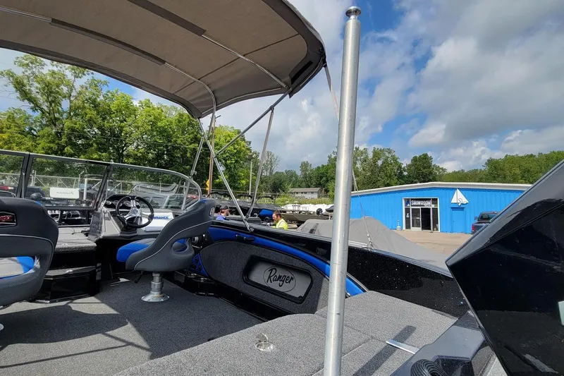 Slide: The Image of 2025 Ranger 2080 Angler boat interior with canopy, showroom in background, sunny day. - 20