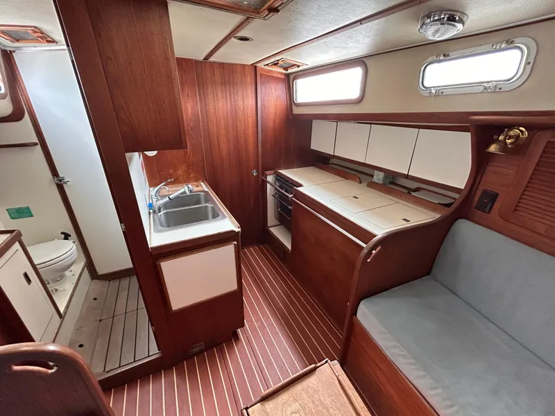 Slide: The Image of 1983 Sabre 38 yacht interior with wood finish, kitchenette, seating, and bathroom. - 13