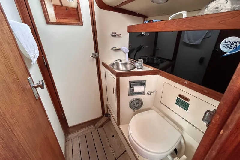 Slide: The Image of 1983 Sabre 38 yacht bathroom with sink, toilet, and wooden accents. - 15