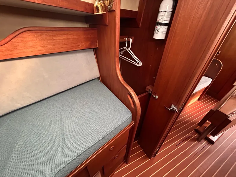Slide: The Image of 1983 Sabre 38 yacht interior with wooden cabinetry, blue cushioned seating, and striped flooring. - 20