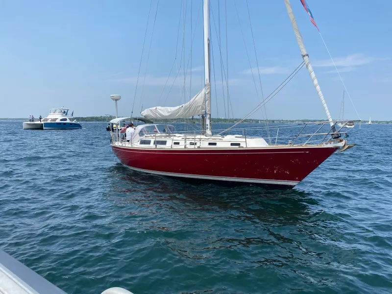 Slide: The Image of 1983 Sabre 38 sailboat with red hull on calm water, clear sky background. - 3
