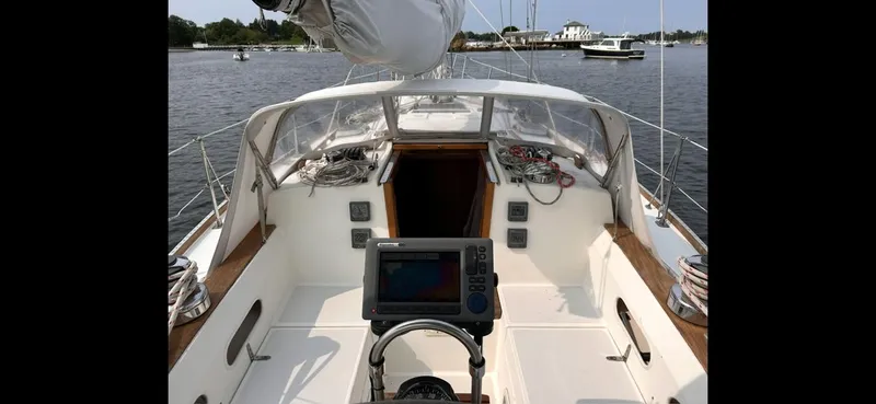 Slide: The Image of 1983 Sabre 38 sailboat cockpit with navigation equipment, docked in a serene marina. - 36