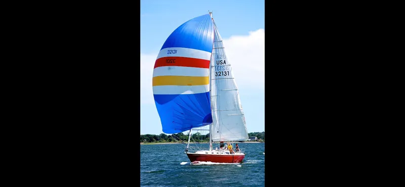 Slide: The Image of 1983 Sabre 38 sailboat with colorful spinnaker sailing on open water. - 5