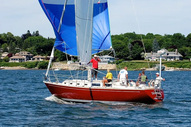 Slide: The Image of 1983 Sabre 38 sailboat with blue sails on a scenic lake. - 6