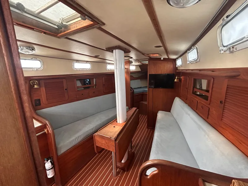 Slide: The Image of 1983 Sabre 38 yacht interior with wooden finish, cushioned seating, and natural light. - 8