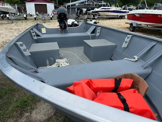 Slide: The Image of 2024 Starcraft Alaskan 13 DLX boat with life jackets and motor, parked on a trailer. - 6