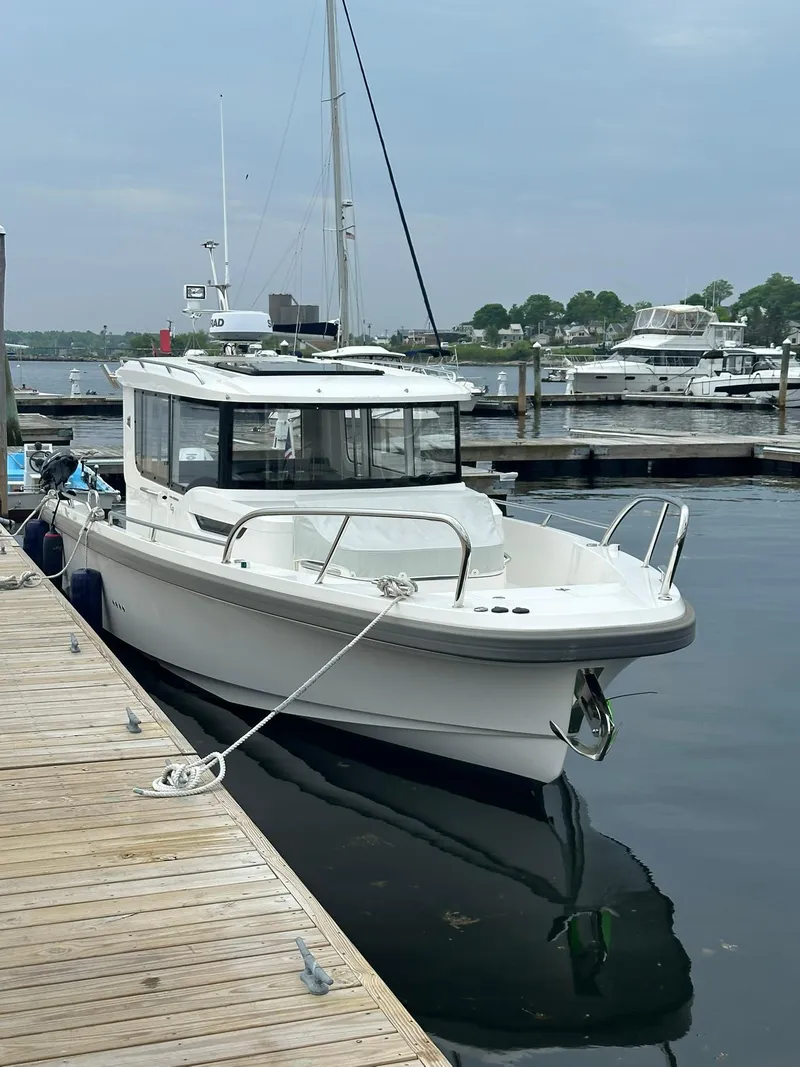 The Image of 2023 Nimbus Commuter 9 boat docked at marina, calm water, overcast sky. - 0