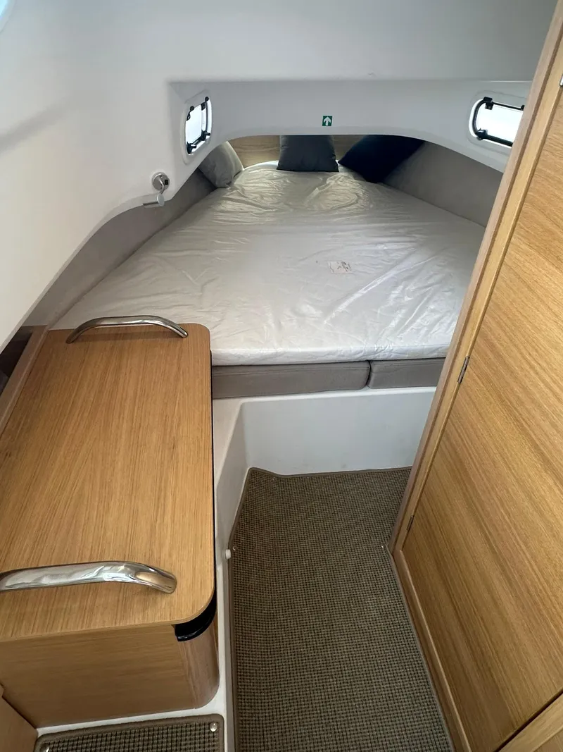 Slide: The Image of 2023 Nimbus Commuter 9 cabin interior with bed, wooden cabinetry, and carpeted floor. - 13