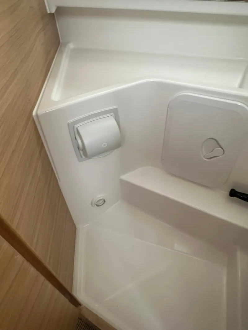 Slide: The Image of 2023 Nimbus Commuter 9 bathroom interior with toilet paper holder and storage compartment. - 16