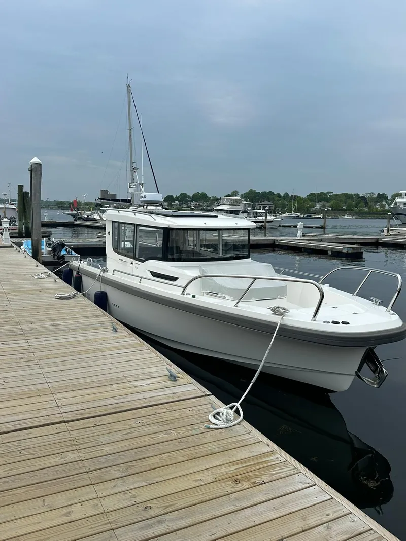Slide: The Image of 2023 Nimbus Commuter 9 boat docked at a marina on a cloudy day. - 4