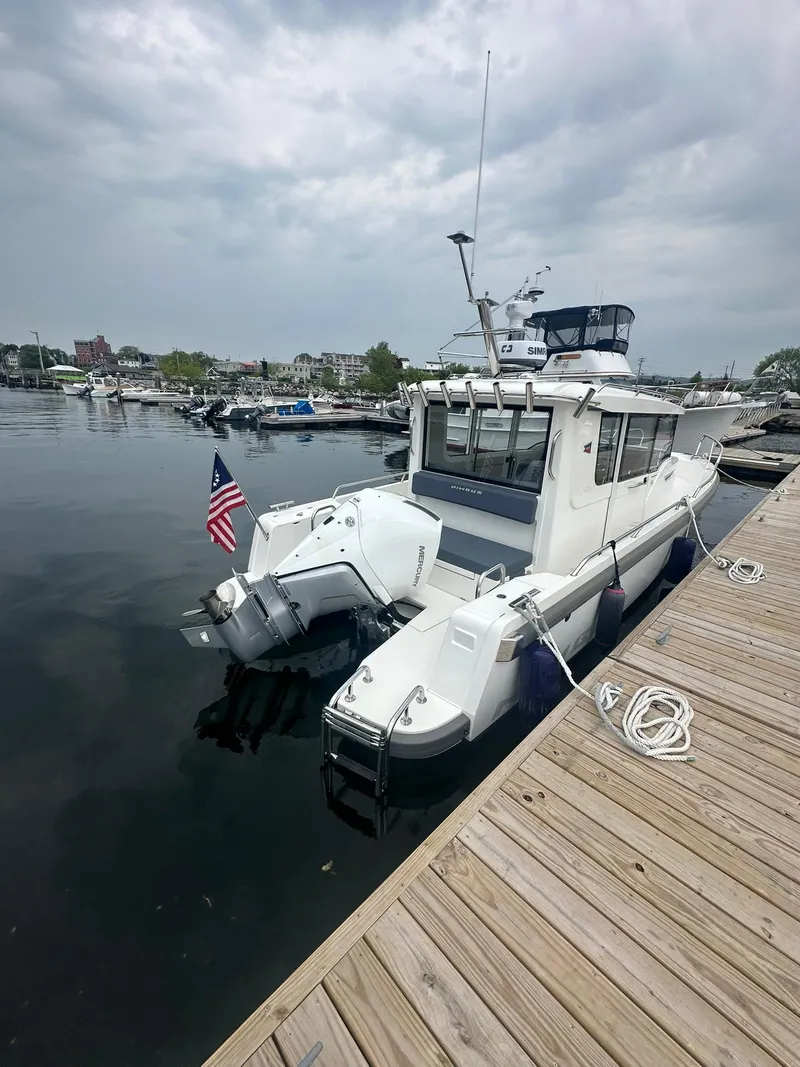 Slide: The Image of 2023 Nimbus Commuter 9 boat docked at marina, overcast sky, American flag displayed. - 5