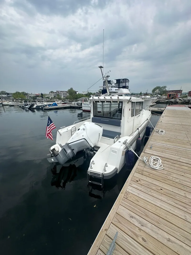 Slide: The Image of Nimbus Commuter 9 boat docked at marina, 2023 model, with American flag, cloudy sky. - 7