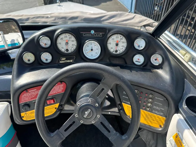 Slide: The Image of 1992 Correct Craft Ski Nautique dashboard with gauges and steering wheel. - 15