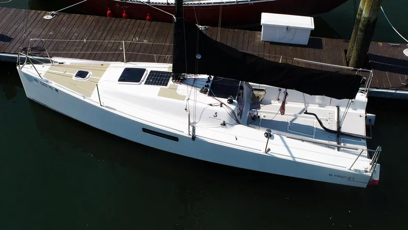 Slide: The Image of 2021 Beneteau First 27 SE sailboat docked, aerial view, sleek design, black sail. - 2