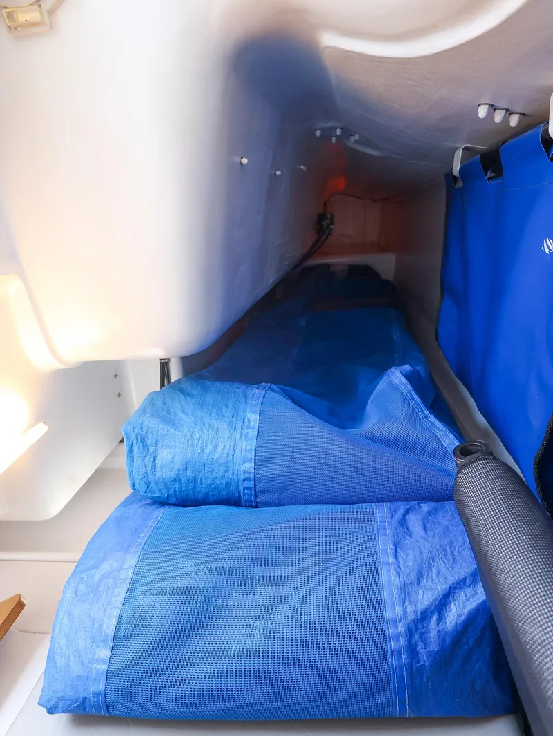Slide: The Image of Interior cabin of 2021 Beneteau First 27 SE sailboat with blue sleeping bags. - 23
