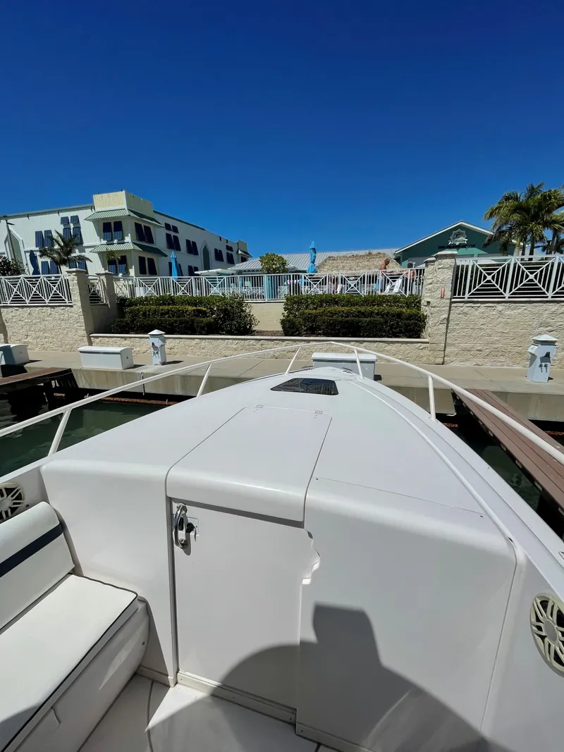 Slide: The Image of 2008 Intrepid 323 Cuddy boat docked near waterfront homes under clear blue sky. - 8