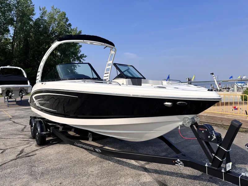 Slide: The Image of 2025 Chaparral 23 SSi boat on trailer, sleek black and white design, parked outdoors. - 1