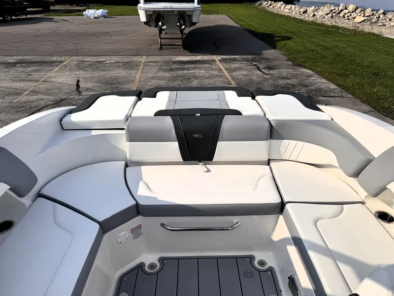 Slide: The Image of 2025 Chaparral 23 SSi boat interior with white and gray seating, docked outdoors. - 13