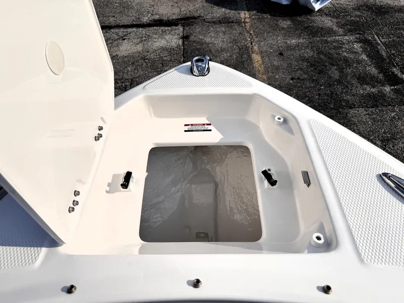 Slide: The Image of 2025 Chaparral 23 SSi boat storage compartment, open lid, white interior, outdoor setting. - 21