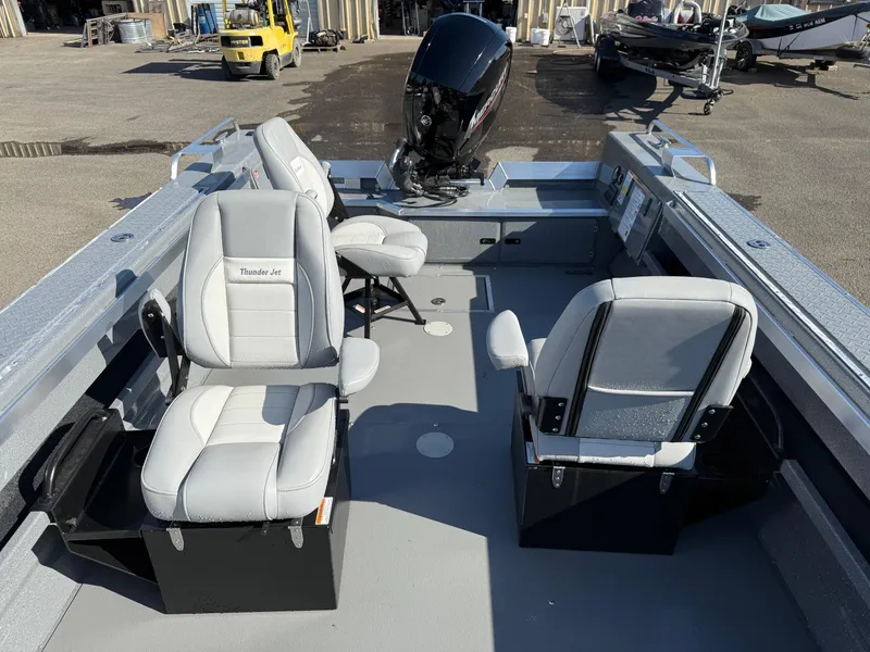 Slide: The Image of 2025 Thunder Jet 209 Rush OT boat interior with seating and motor, parked outdoors. - 20