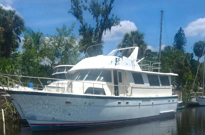 The Image of 1982 Hatteras 61 Motor Yacht docked on a sunny day, surrounded by lush greenery. - 1