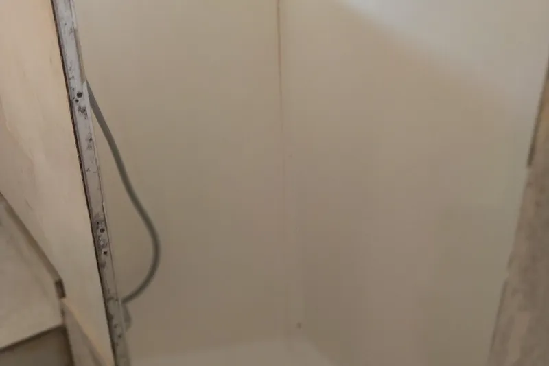 Slide: The Image of Shower area inside 1982 Hatteras 61 Motor Yacht, featuring simple white interior. - 11