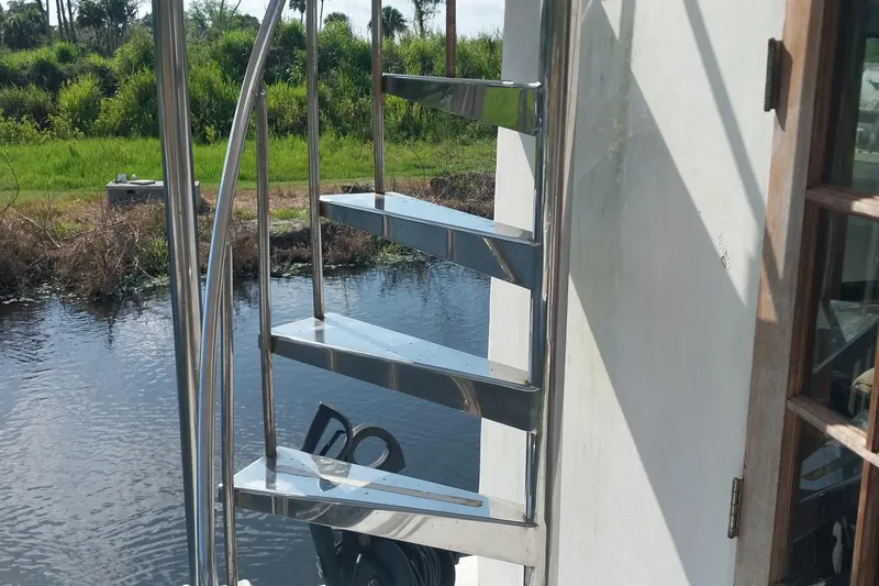 Slide: The Image of Stainless steel spiral staircase on 1982 Hatteras 61 Motor Yacht by the water. - 5