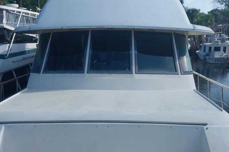 Slide: The Image of 1982 Hatteras 61 Motor Yacht with large windows, docked in a marina. - 6