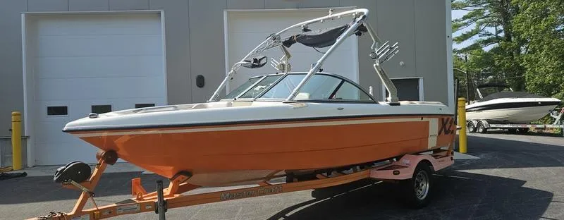 Slide: The Image of 2007 MasterCraft X1 boat in orange on a trailer, parked outside a garage. - 27