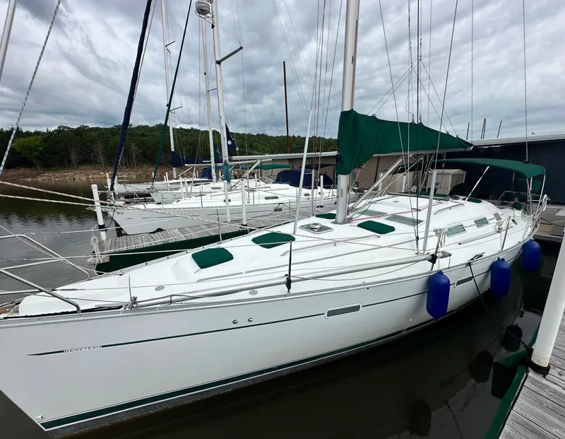 The Image of 2004 Beneteau 393 sailboat docked, featuring green covers and blue fenders. - 0
