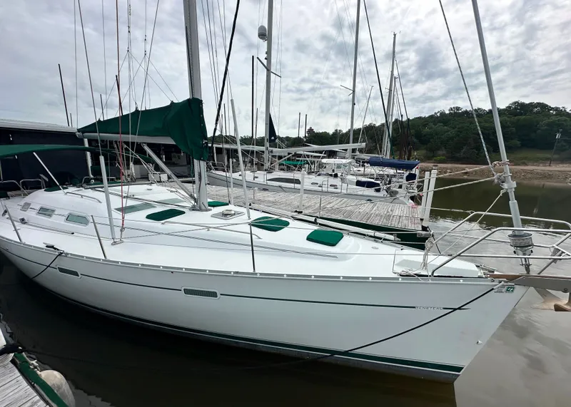 Slide: The Image of 2004 Beneteau 393 sailboat docked at marina, featuring green accents and overcast sky. - 10