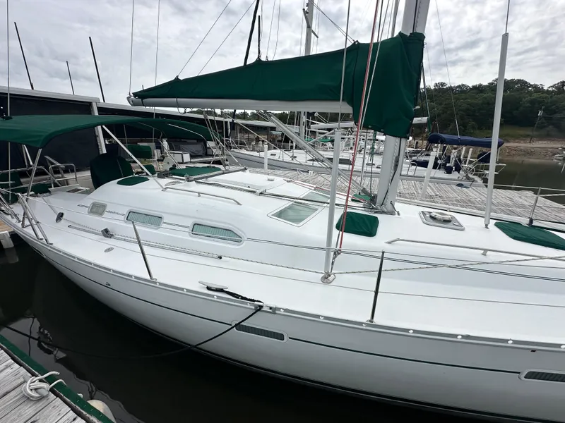Slide: The Image of 2004 Beneteau 393 sailboat docked, featuring green covers and sleek white design. - 13