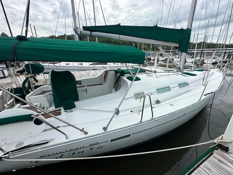 Slide: The Image of 2004 Beneteau 393 sailboat docked, featuring green covers and sleek white design. - 14
