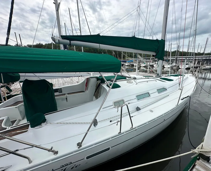 Slide: The Image of 2004 Beneteau 393 sailboat docked, featuring green covers and sleek white design. - 15