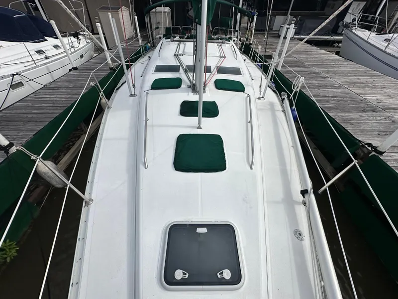 Slide: The Image of 2004 Beneteau 393 sailboat docked, featuring a clean white deck and green accents. - 29