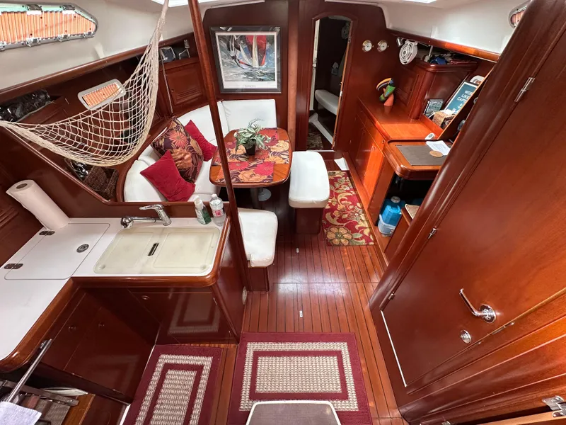 Slide: The Image of Interior of 2004 Beneteau 393 sailboat with wood finish, kitchen, and seating area. - 34