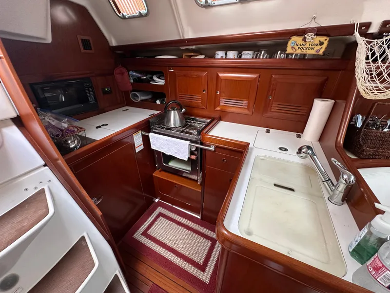 Slide: The Image of Cozy kitchen in 2004 Beneteau 393 sailboat with wooden cabinetry and modern appliances. - 44
