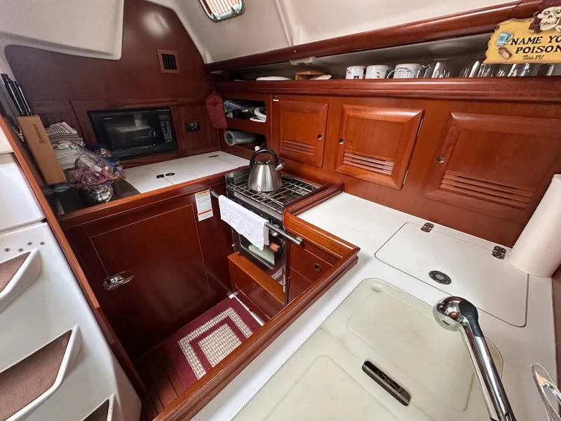 Slide: The Image of 2004 Beneteau 393 yacht kitchen with wooden cabinets, stove, and sink. - 45