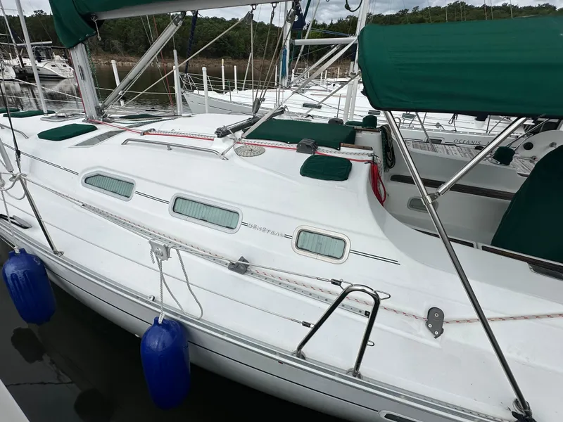 Slide: The Image of 2004 Beneteau 393 sailboat docked, featuring green covers and blue fenders. - 5