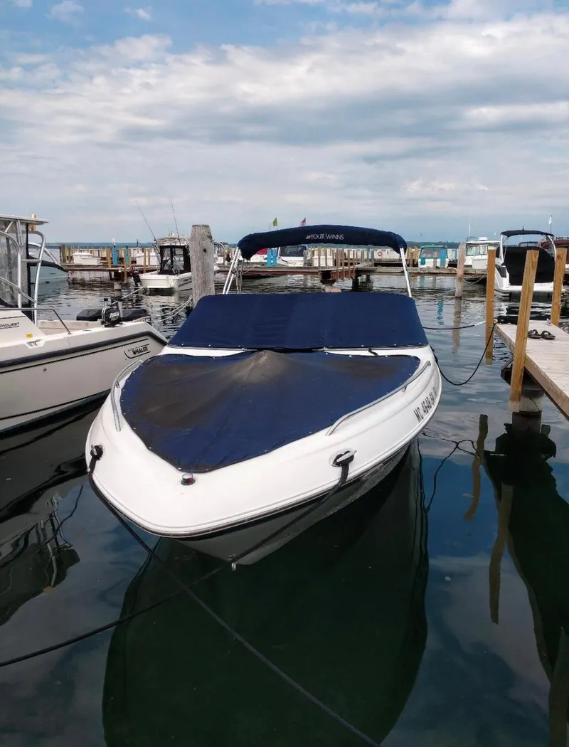 Slide: The Image of 2002 Four Winns 260 Horizon boat docked with cover on, under cloudy sky. - 2