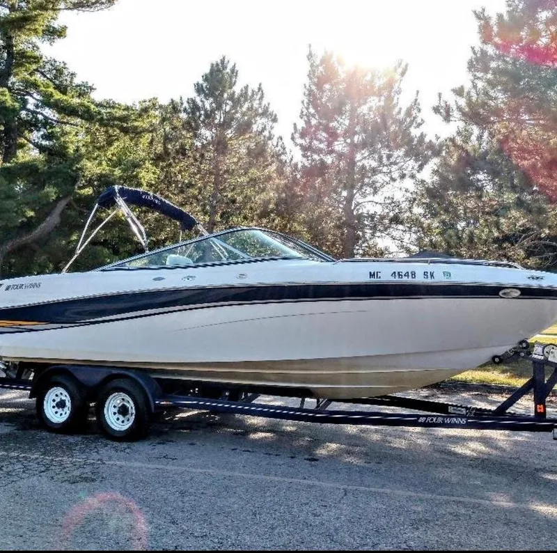 Slide: The Image of 2002 Four Winns 260 Horizon boat on trailer, surrounded by trees and sunlight. - 3