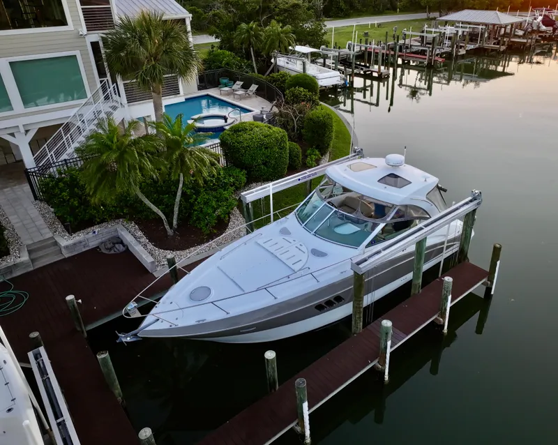 Slide: The Image of 2009 Cruisers Yachts 360 Express docked by a waterfront home with lush greenery. - 17