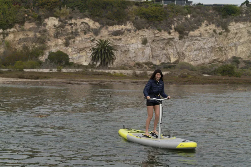 Slide: The Image of Woman enjoying a ride on a 2025 Hobie iEclipse pedalboard in a scenic waterway. - 3
