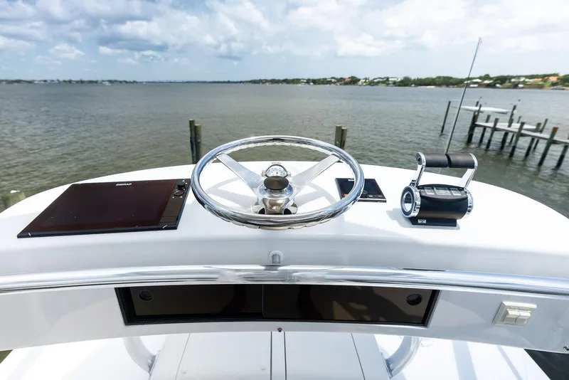 Slide: The Image of 2010 Viking 52 Open yacht helm with steering wheel and throttle, overlooking serene waters. - 42