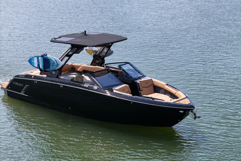 Slide: The Image of 2026 Cobalt R8 Surf boat on water, featuring sleek design and surfboard rack. - 2