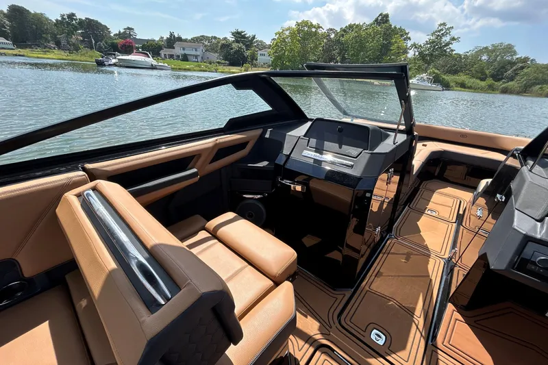 Slide: The Image of 2026 Cobalt R8 Surf boat interior with luxurious seating and modern dashboard on a scenic lake. - 34
