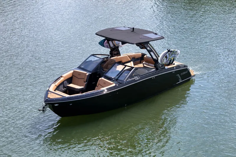 Slide: The Image of 2026 Cobalt R8 Surf boat on calm water, featuring sleek black design and tan interior. - 4